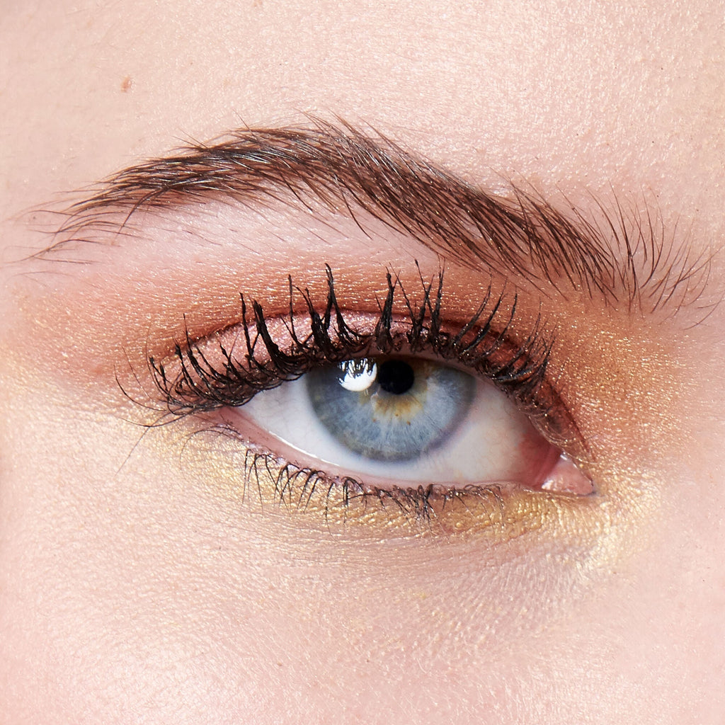 Close-up of a blue eye with eye makeup on a beige background